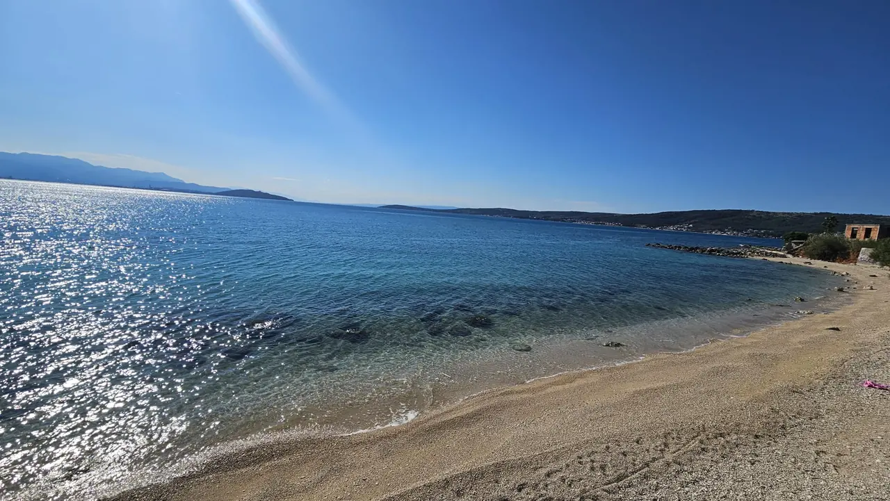Photograph, May 2026 — The same beach, the cove